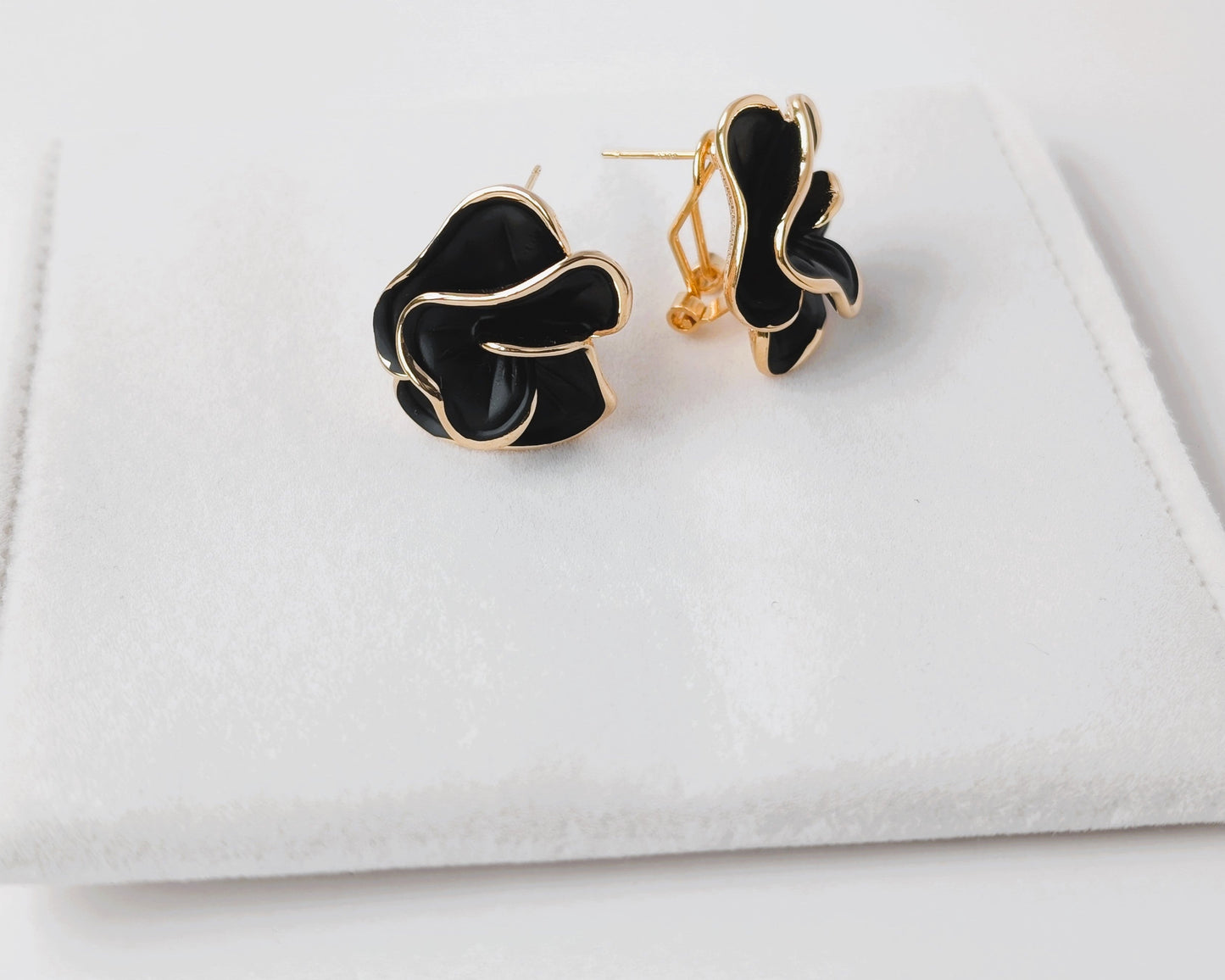 Black and gold earrings on a white surface
