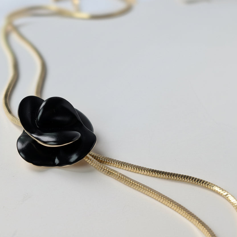Black flower-shaped pendant on a gold chain 
