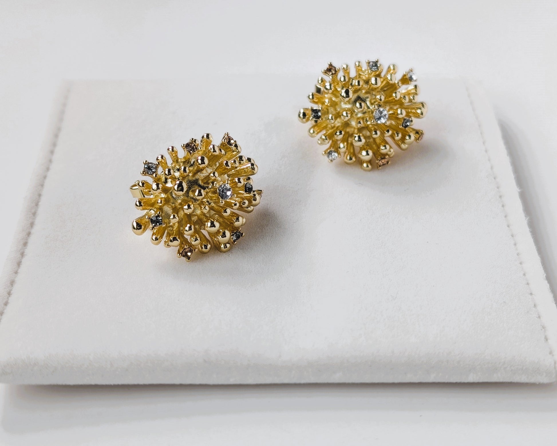 Gold earrings with gemstones on a white surface
