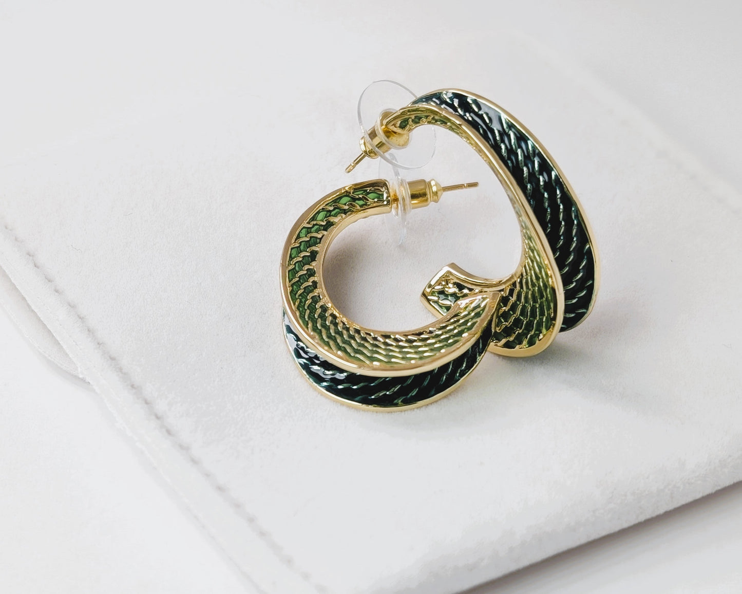 Gold hoop earrings with green and black pattern on a white surface