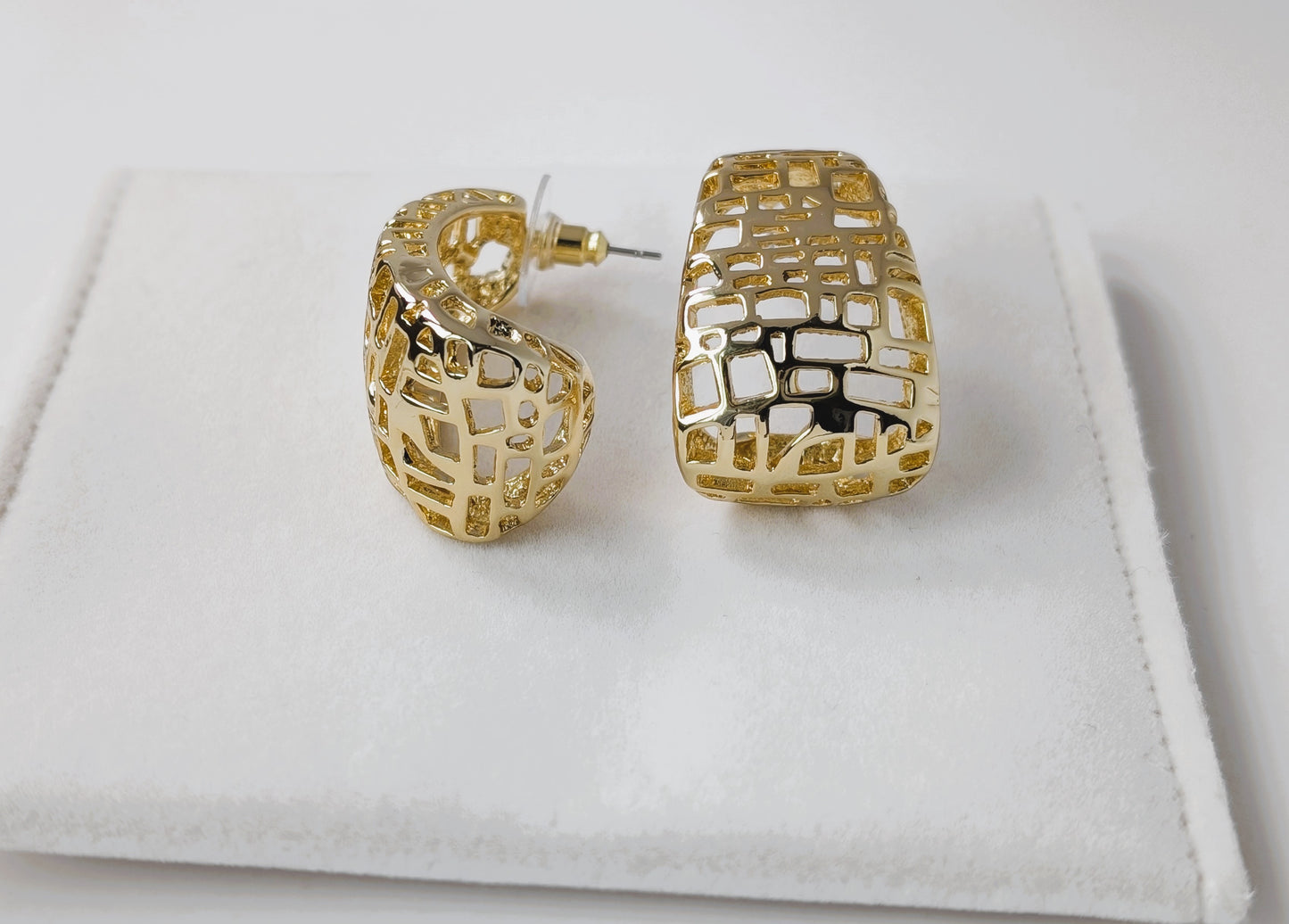 Gold hoop earrings on a white fabric background