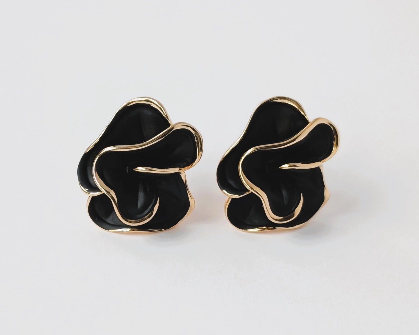 Pair of black and gold earrings on a white background