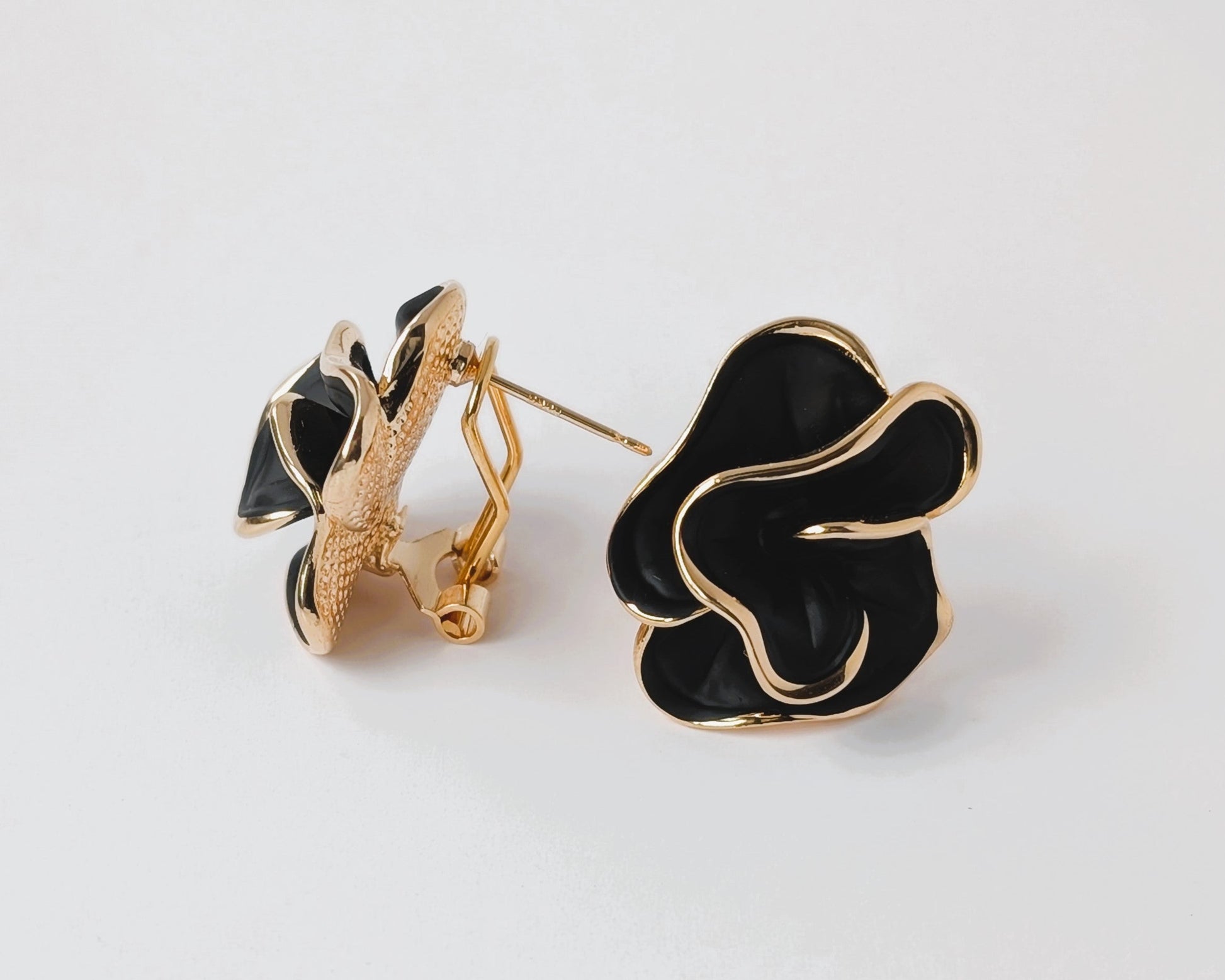 Black floral earrings with gold accents on a white background